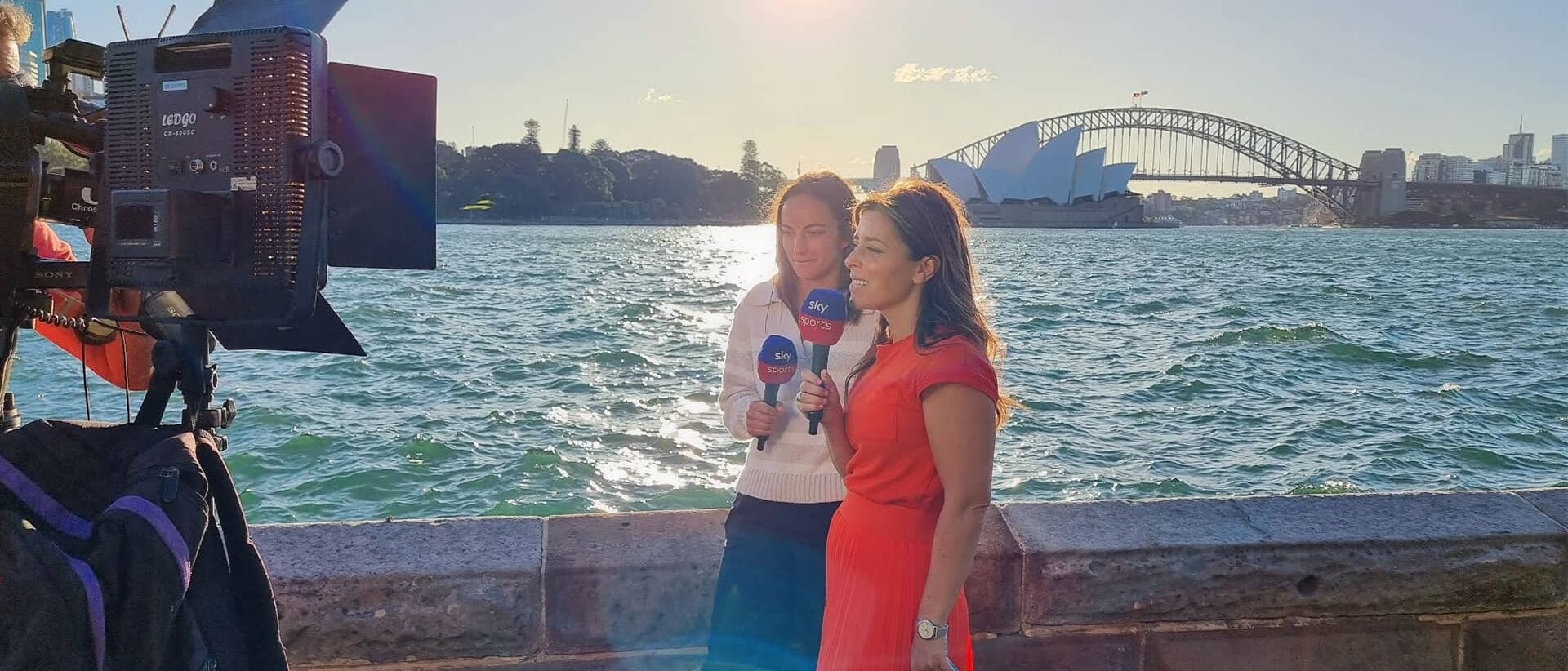 Couple of women talking to camera with Sidney Opera building in background