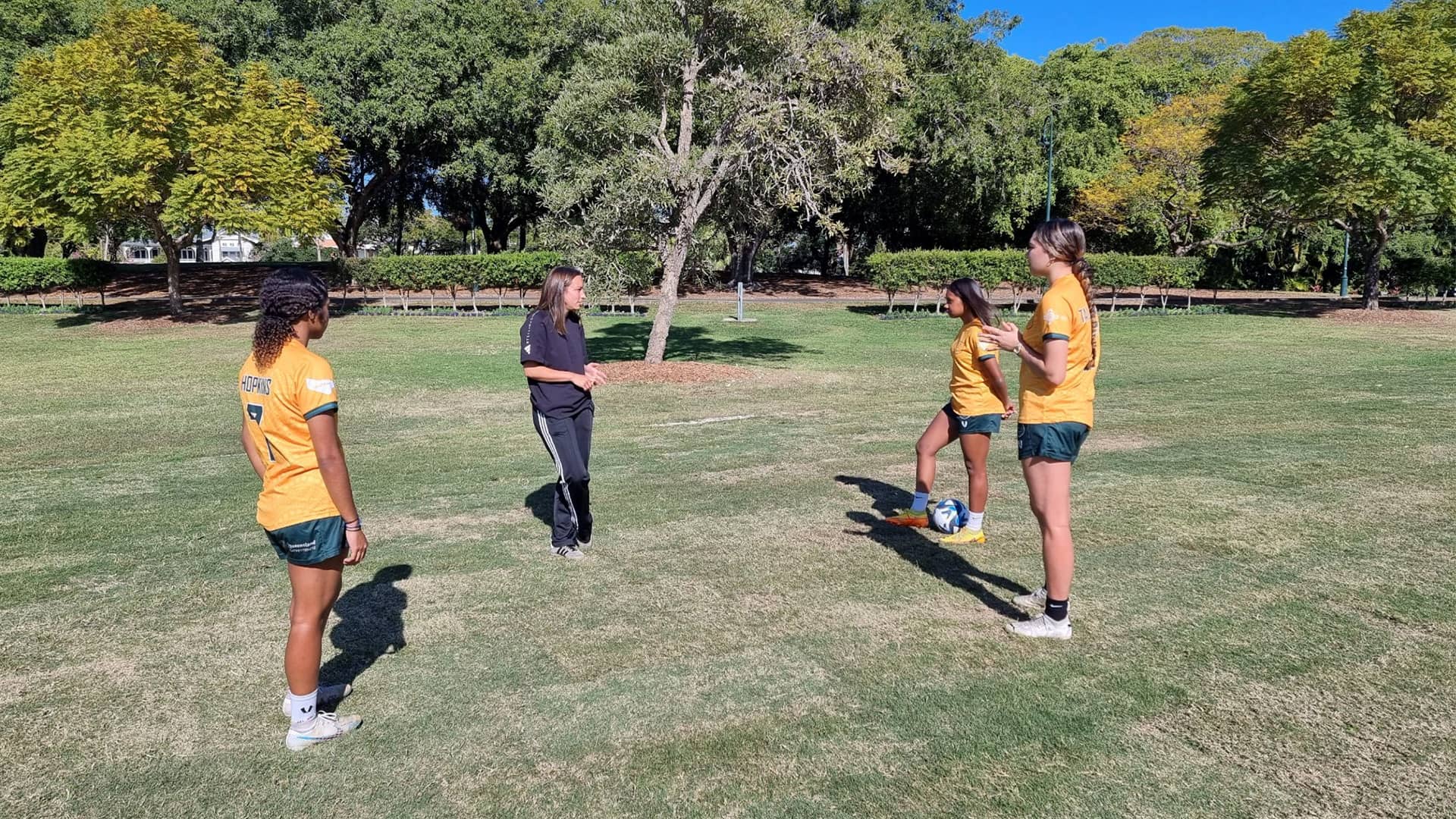 Group of four women football players in park with football ball