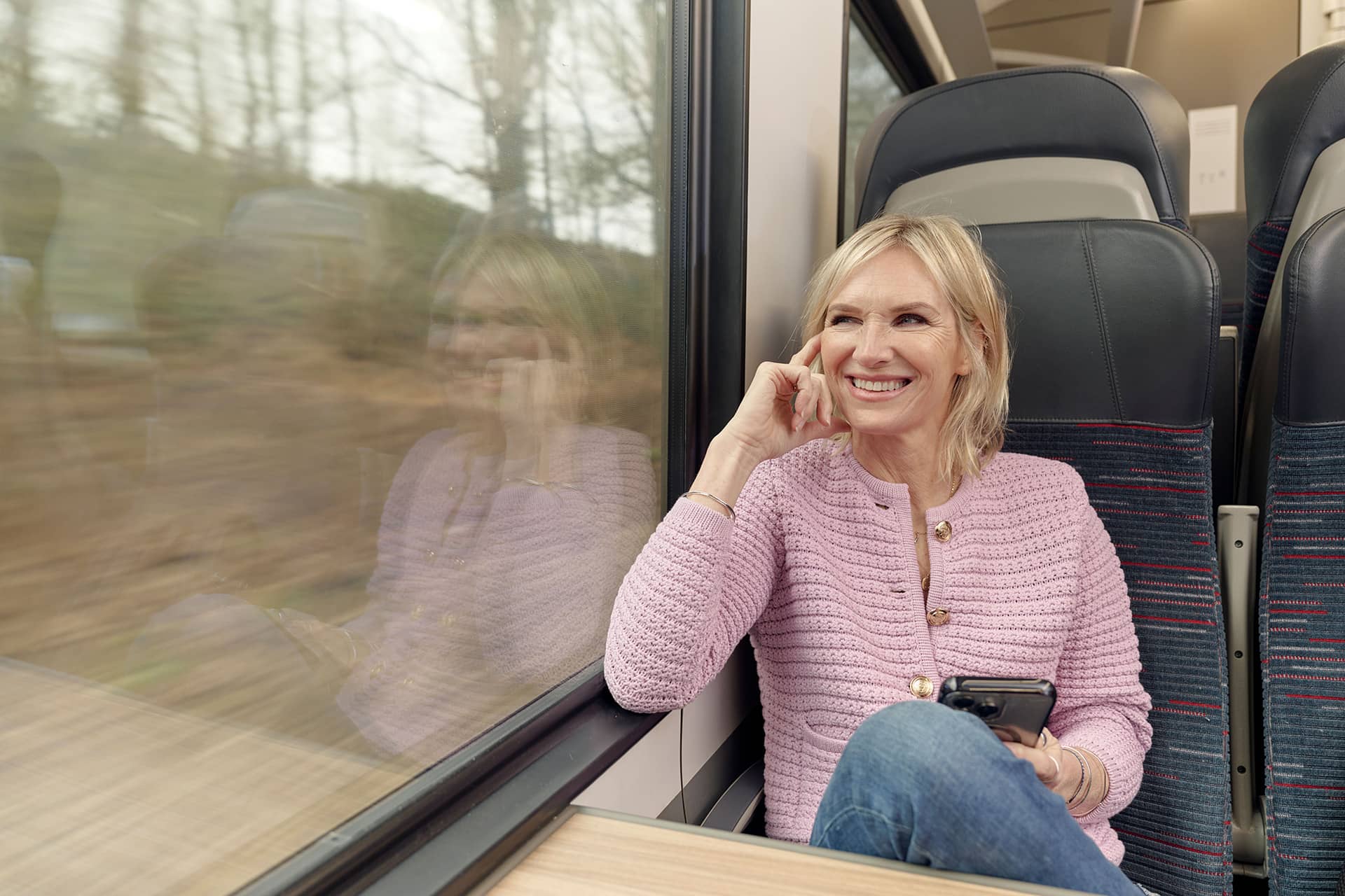 Woman looking out of the window on train holding the mobile phone