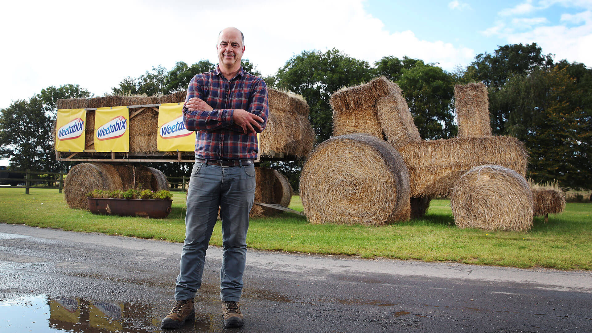 A farmer with a tractor made of hay and Weetabix signage