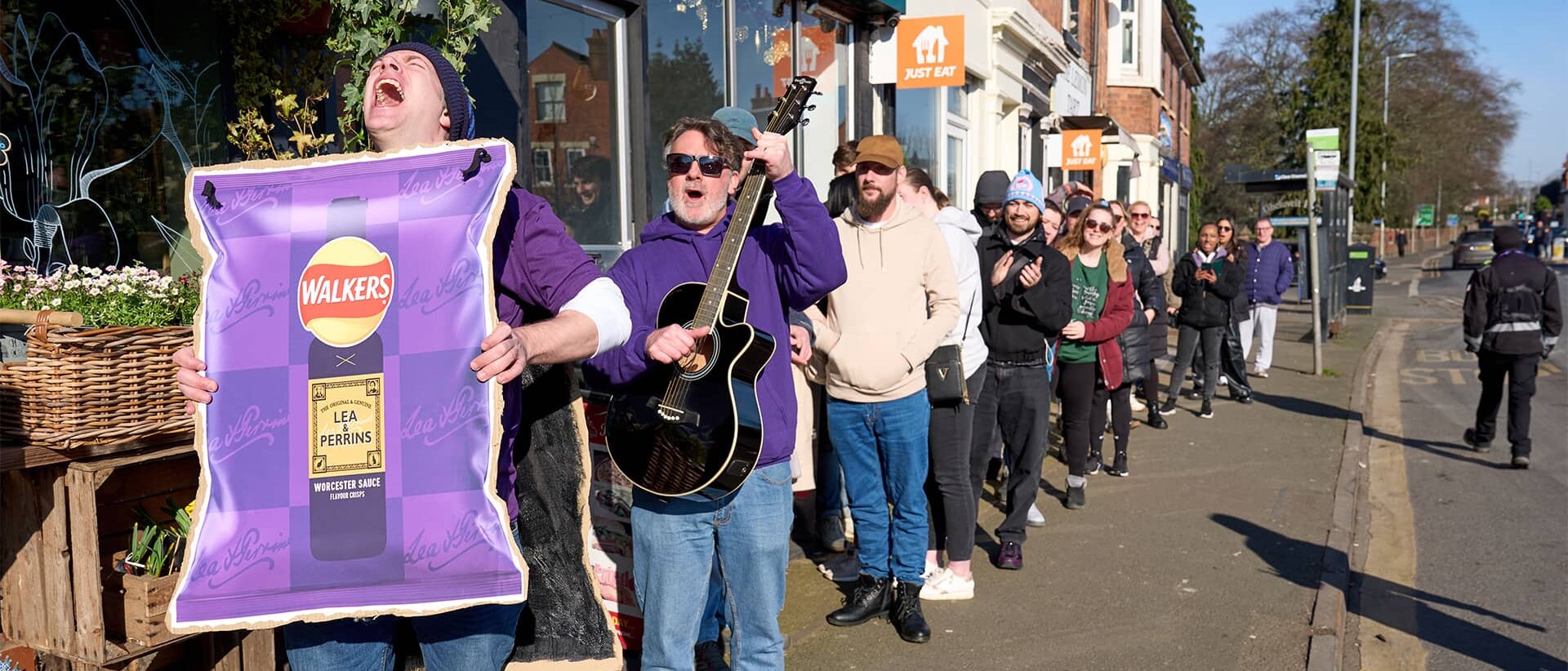 Queue of excited people, first is holding a paper board with Walkers poster