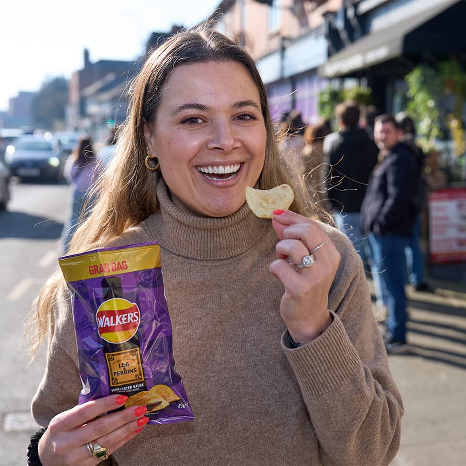 Smiling woman holding pack of Walkers chips